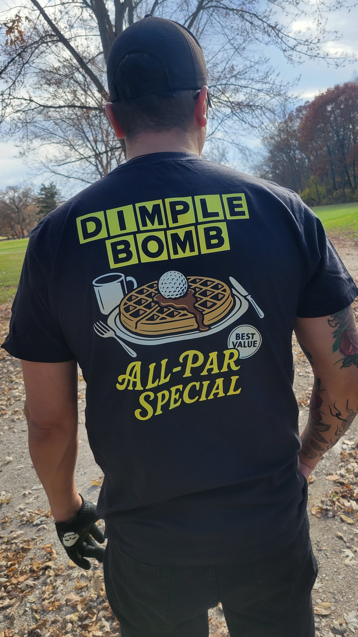 Person wearing a black t-shirt with a humorous graphic and text outdoors.