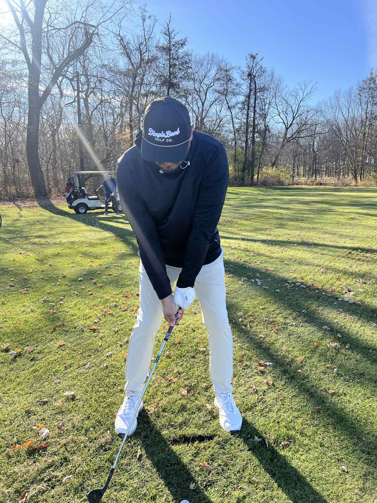 Person playing golf on a grassy course with trees in the background
