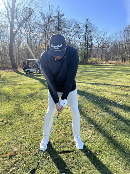 Person playing golf on a grassy course with trees in the background